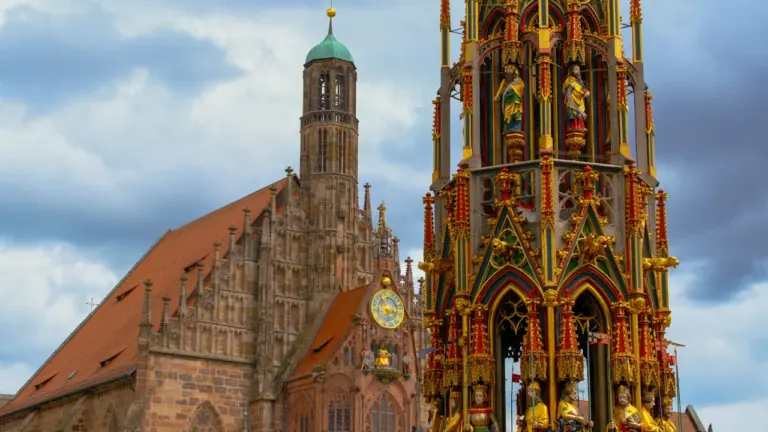 Prunkvoller Brunnen vor einer historischen Kirche in einer deutschen Stadt an einem Tag.