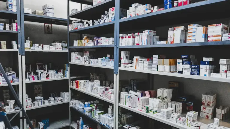 Vollgefüllte Regale mit Medikamentenpackungen in einer organisierten Apotheken-Umgebung.