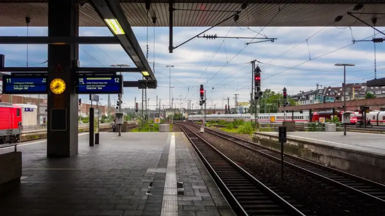 Moderner Bahnsteig mit Gleisen und Oberleitungen an einem deutschen Bahnhof.