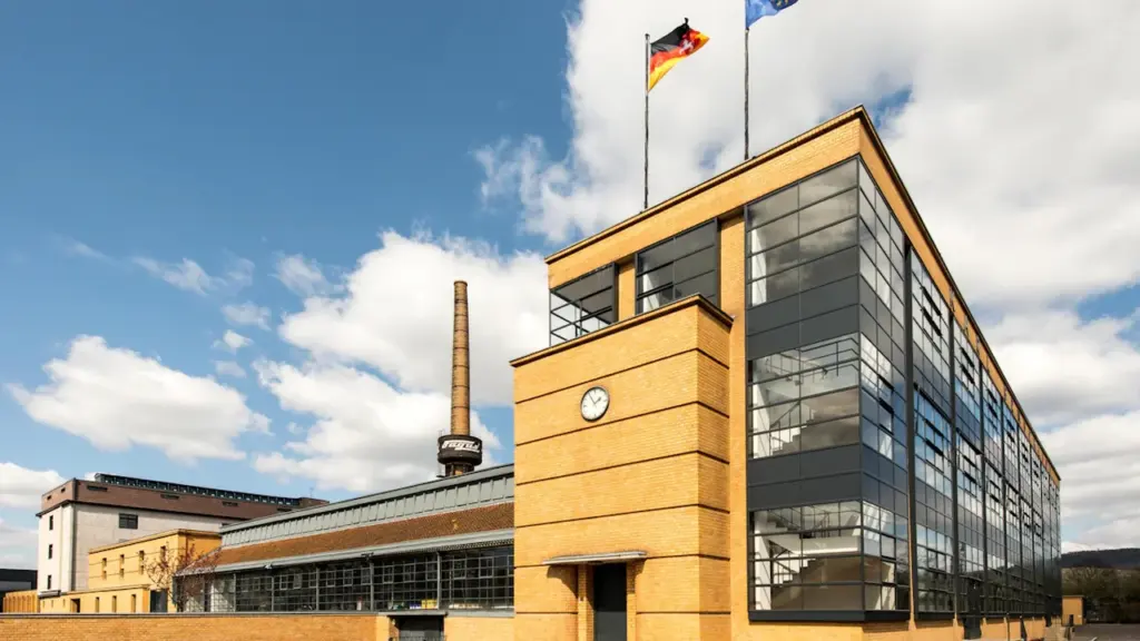 Ein historisches deutsches Industriegebäude mit wehender Deutschlandfahne unter einem blauen Himmel.