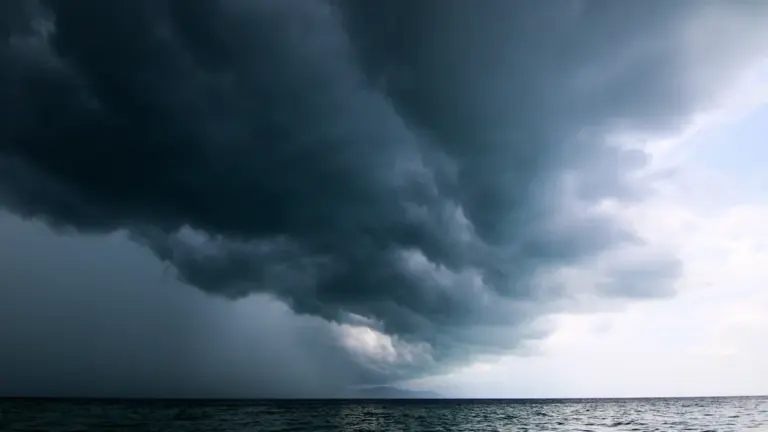 Dunkle Gewitterwolken ziehen über einem See auf und kündigen ein Unwetter an.