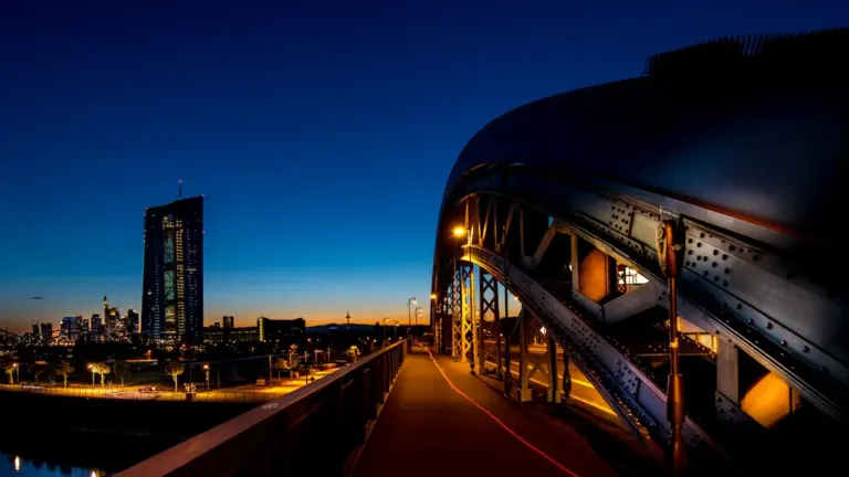 Die Europäische Zentralbank in Frankfurt am Main bei nächtlicher Beleuchtung an der Osthafenbrücke.