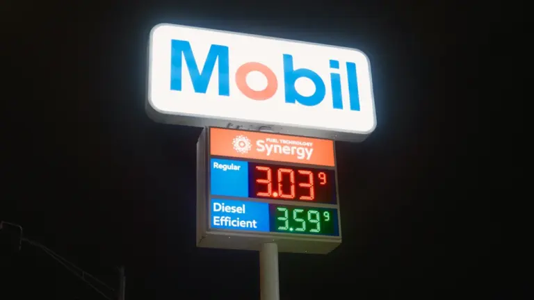 Beleuchtetes Preisschild einer Tankstelle bei Nacht mit gut lesbaren Kraftstoffpreisen für Autofahrer.