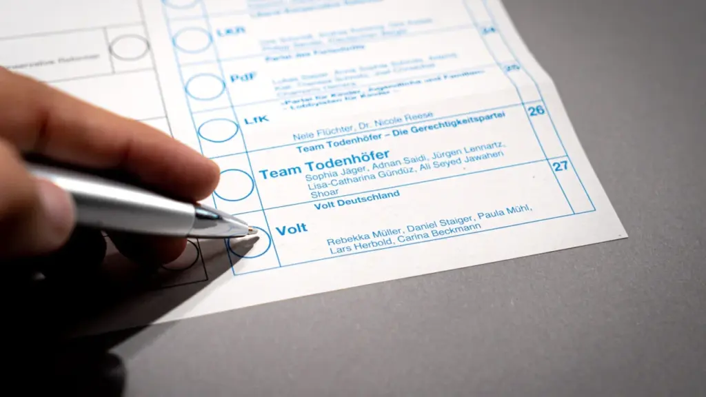 Eine Hand hält einen Stift über einem deutschen Wahlzettel für die Bundestagswahl.
