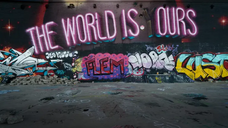 Bunte Graffiti-Kunst mit dem Schriftzug The World Is Yours an einer Betonwand.