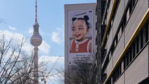 Fernsehturm Berlin neben einem großen Plakat eines lächelnden Kindes im Stadtzentrum.