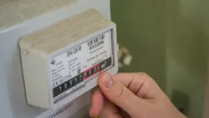 Eine Hand beim Ablesen eines Stromzählers in einer privaten Wohnung.