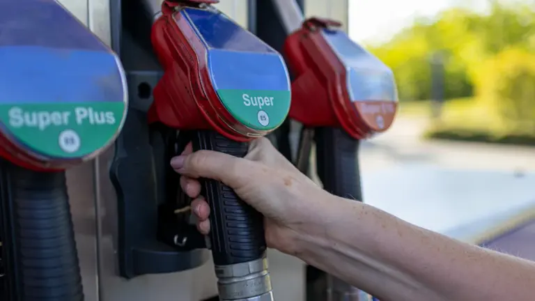 Nahaufnahme einer Hand, die eine Zapfpistole an einer deutschen Tankstelle hält.