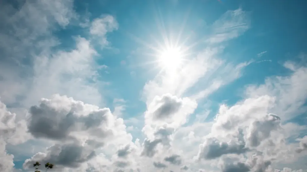 Heller blauer Himmel mit weißen Wolken und strahlender Sonne an einem Sommertag.