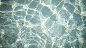 Klares, blaues Wasser mit sanften Lichtreflexionen an einem sonnigen Tag in der Schweiz.