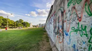Blick auf ein historisches Teilstück der Berliner Mauer mit farbenfrohen Graffitis bei Tageslicht.