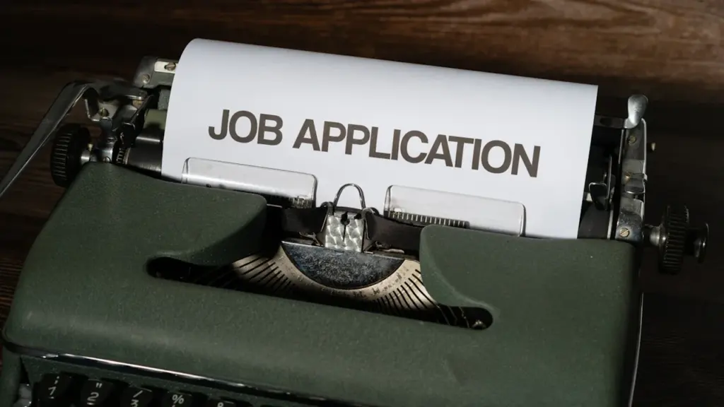 Eine historische Schreibmaschine mit einem Blatt Papier auf dem Job Application steht.