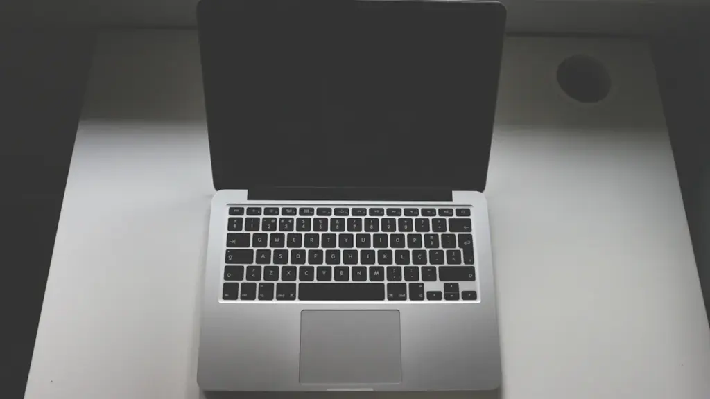 Ein offener, silberner Laptop auf einem weißen Tisch in einem hellen Raum.