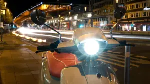 Ein beleuchteter E-Scooter bei Nacht vor einer städtischen Kulisse in Deutschland.