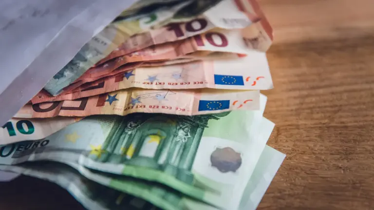 Nahaufnahme von Euro-Banknoten in einem Umschlag auf einem hölzernen Untergrund.