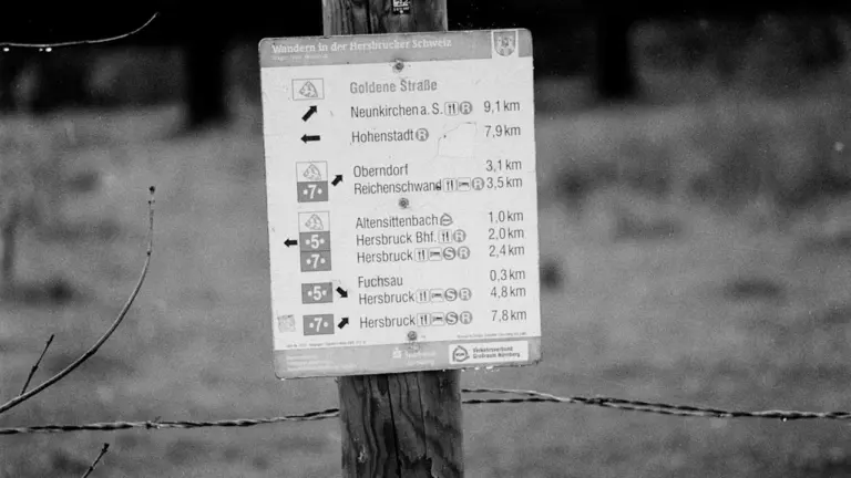 Ein hölzernes Wegweiserschild an einem Wanderweg in der deutschen Mittelgebirgslandschaft.