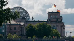 Das Reichstagsgebäude in Berlin mit wehenden deutschen Flaggen bei klarem Sommerwetter.